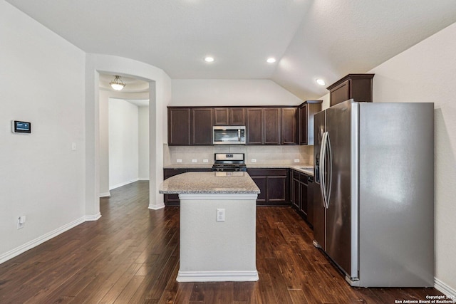 kitchen featuring light stone countertops, dark brown cabinetry, a kitchen island, and stainless steel appliances