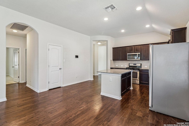 kitchen featuring dark brown cabinetry, stainless steel appliances, dark wood-type flooring, a kitchen island, and visible vents