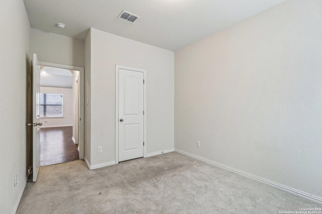 unfurnished bedroom with light carpet, baseboards, and visible vents