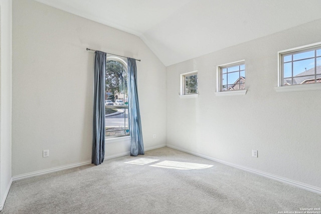 empty room featuring lofted ceiling, light carpet, and baseboards