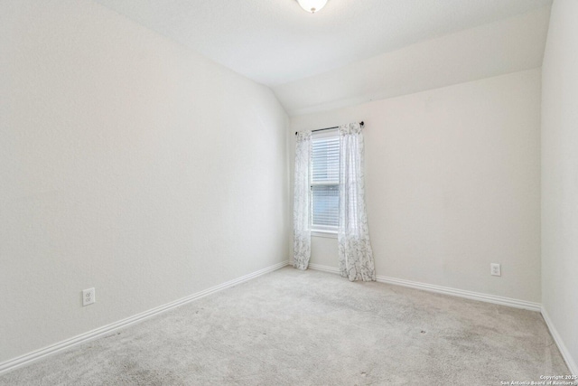 empty room with light carpet, baseboards, and lofted ceiling