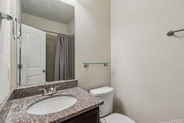 full bath with a textured wall, a shower with shower curtain, vanity, and toilet