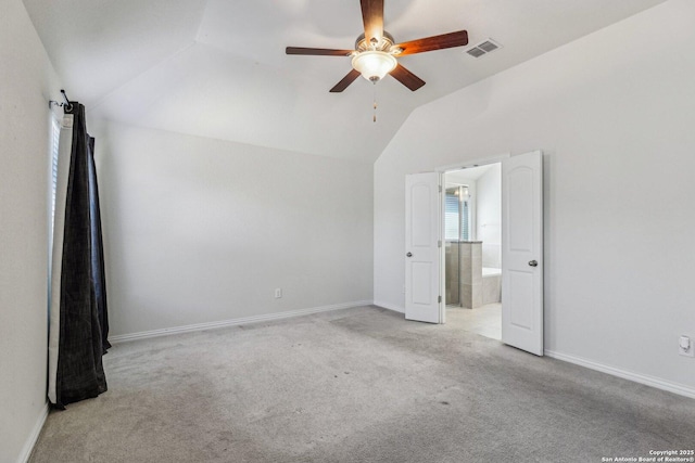 spare room featuring light colored carpet, visible vents, a ceiling fan, vaulted ceiling, and baseboards