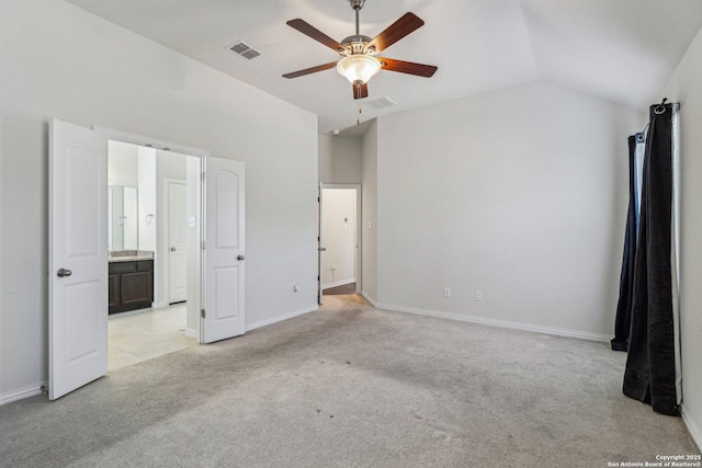 unfurnished bedroom featuring visible vents, vaulted ceiling, connected bathroom, and light colored carpet