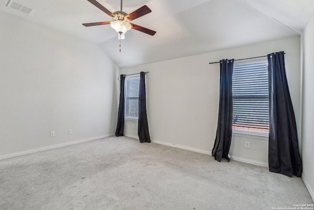 unfurnished room with baseboards, visible vents, a ceiling fan, light colored carpet, and vaulted ceiling