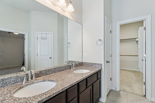 full bathroom with double vanity, tile patterned flooring, a sink, and a walk in closet