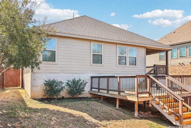 rear view of house with roof with shingles, stairs, fence, a deck, and a yard