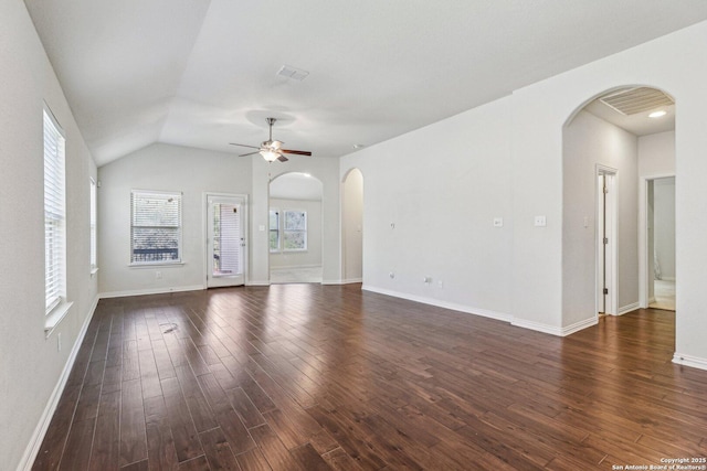 unfurnished living room featuring arched walkways, ceiling fan, dark wood-type flooring, visible vents, and baseboards