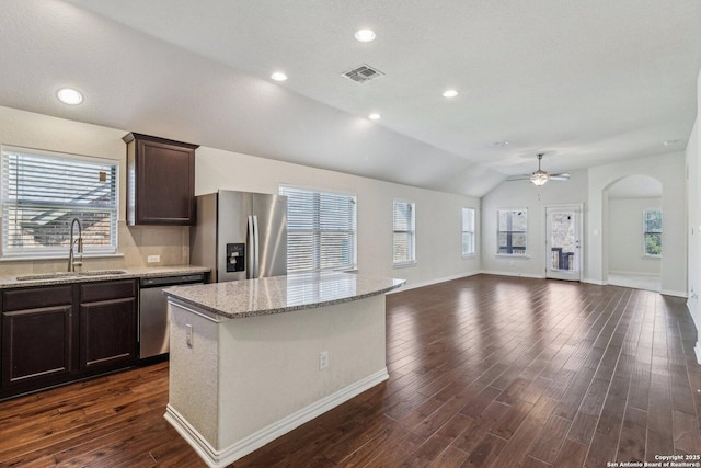 kitchen with a kitchen island, appliances with stainless steel finishes, open floor plan, dark brown cabinets, and a sink