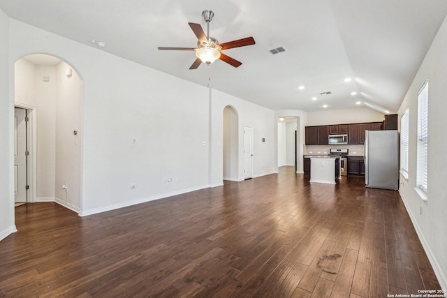 unfurnished living room featuring arched walkways, visible vents, dark wood-type flooring, vaulted ceiling, and ceiling fan