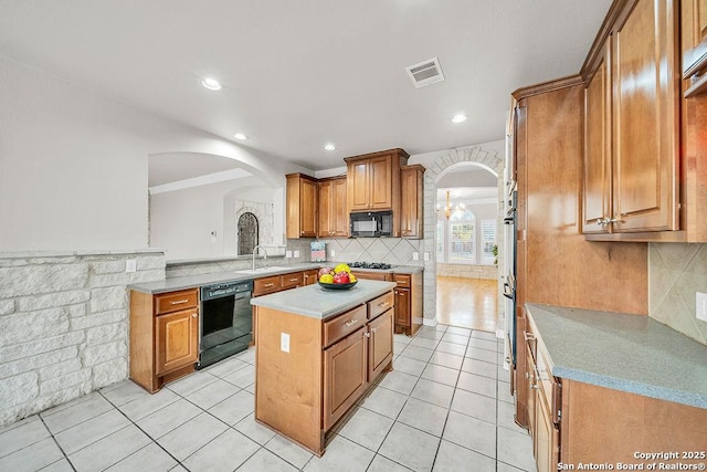 kitchen featuring visible vents, arched walkways, a center island, light countertops, and black appliances
