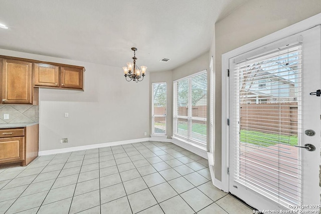 unfurnished dining area with visible vents, a notable chandelier, baseboards, and light tile patterned floors