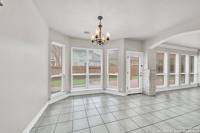 unfurnished dining area featuring light tile patterned floors, arched walkways, a notable chandelier, visible vents, and baseboards