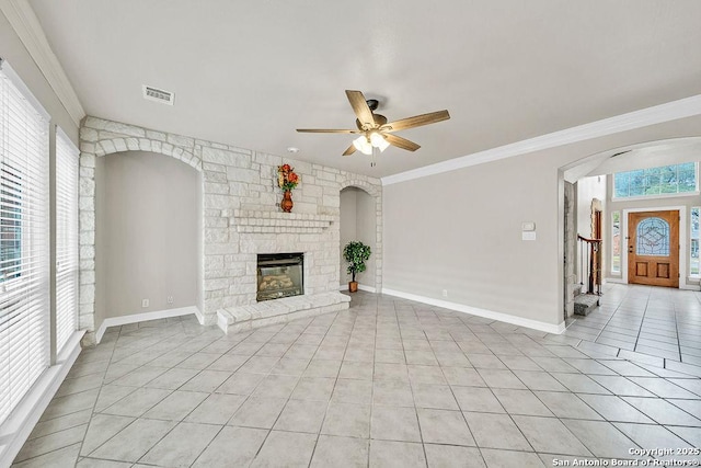 unfurnished living room featuring arched walkways, crown molding, a fireplace, light tile patterned floors, and visible vents