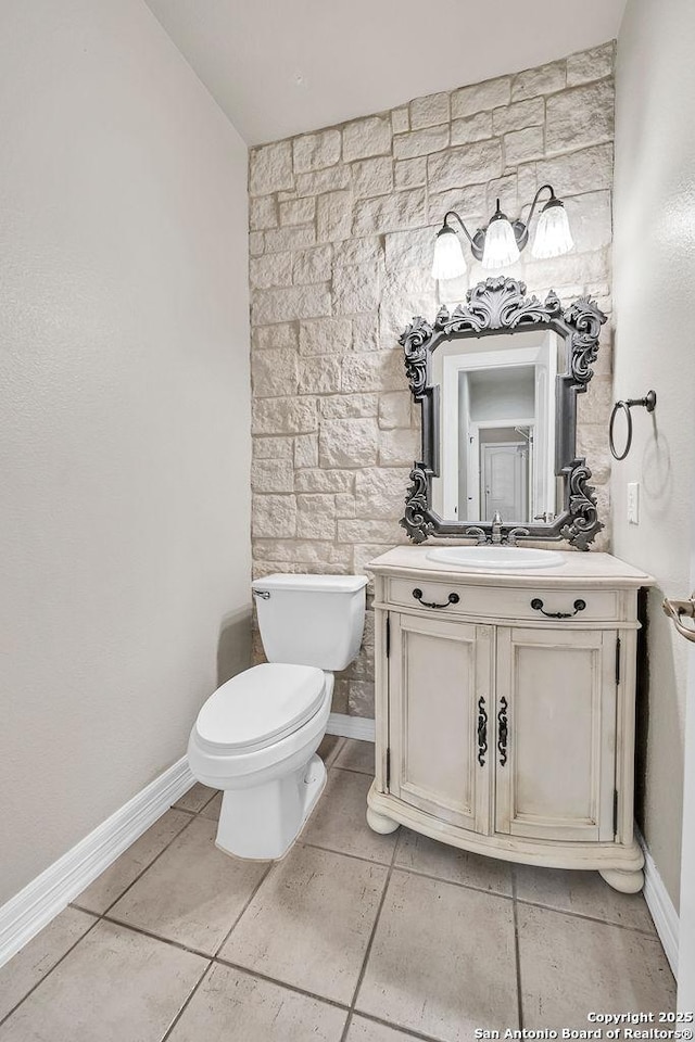 half bath featuring toilet, tile patterned floors, baseboards, and vanity