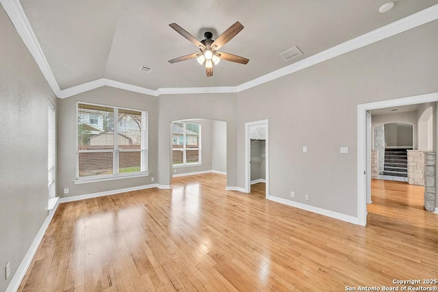 interior space with arched walkways, ornamental molding, a ceiling fan, and light wood-style floors