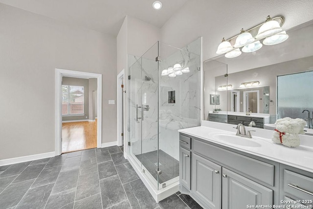 bathroom with a marble finish shower, vanity, and baseboards