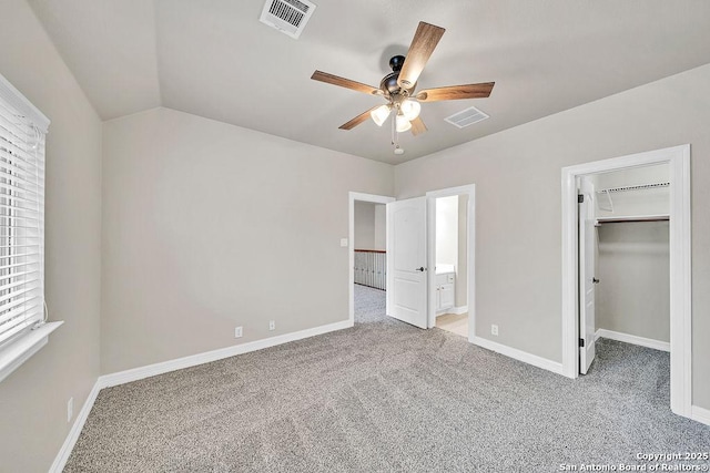 unfurnished bedroom featuring a walk in closet, visible vents, light carpet, and baseboards