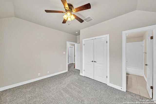 unfurnished bedroom with lofted ceiling, light carpet, baseboards, and a closet