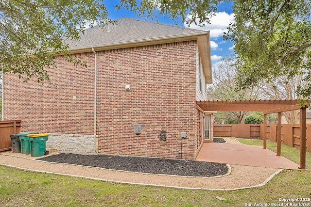 view of home's exterior featuring brick siding, a patio, a shingled roof, a pergola, and a fenced backyard