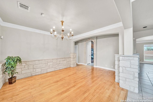 unfurnished dining area with ornamental molding, arched walkways, visible vents, and wood finished floors