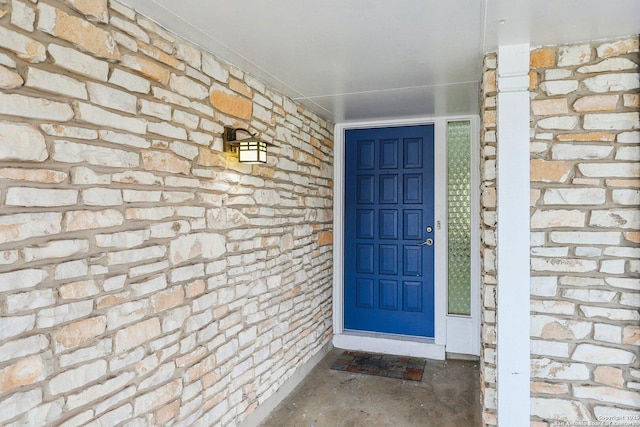 view of exterior entry with stone siding and brick siding