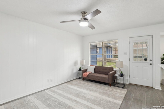 sitting room with ceiling fan, baseboards, light wood-style flooring, and a textured ceiling