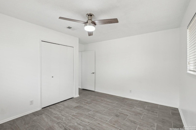 unfurnished bedroom featuring a closet, visible vents, ceiling fan, a textured ceiling, and baseboards