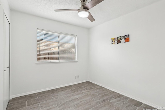 spare room featuring ceiling fan, a textured ceiling, and baseboards