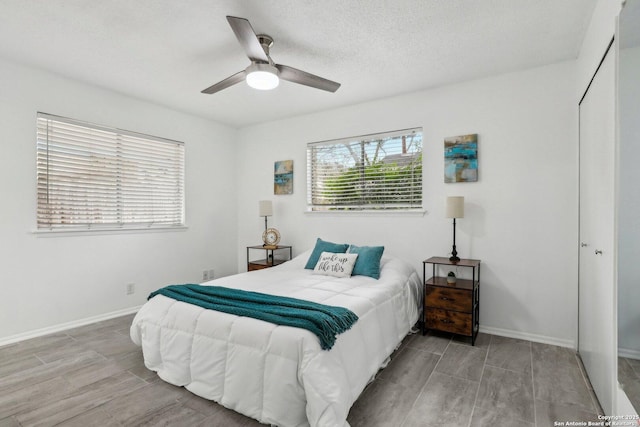 bedroom featuring ceiling fan, baseboards, and a textured ceiling