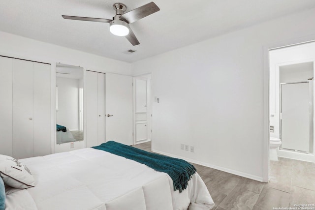 bedroom featuring two closets, visible vents, ensuite bathroom, wood finished floors, and baseboards