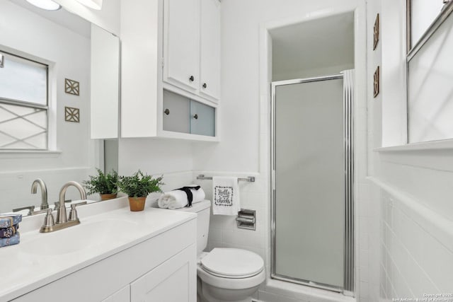 full bathroom featuring a shower stall, a wainscoted wall, tile walls, and vanity