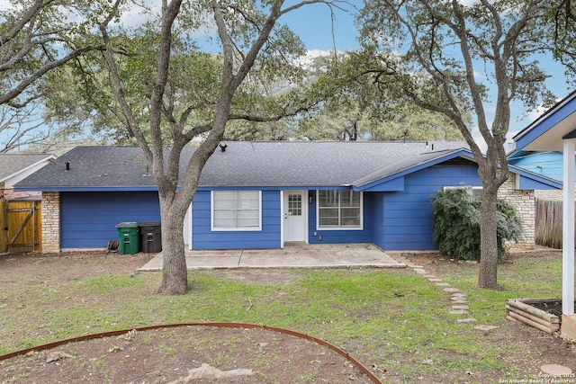 single story home featuring a shingled roof, stone siding, fence, a patio area, and a front yard