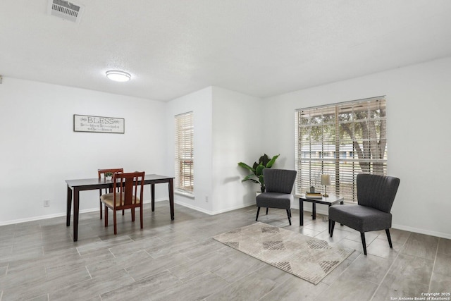 living area featuring baseboards, visible vents, and a textured ceiling