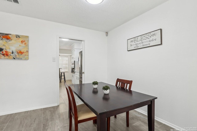 dining room with visible vents, a textured ceiling, and baseboards