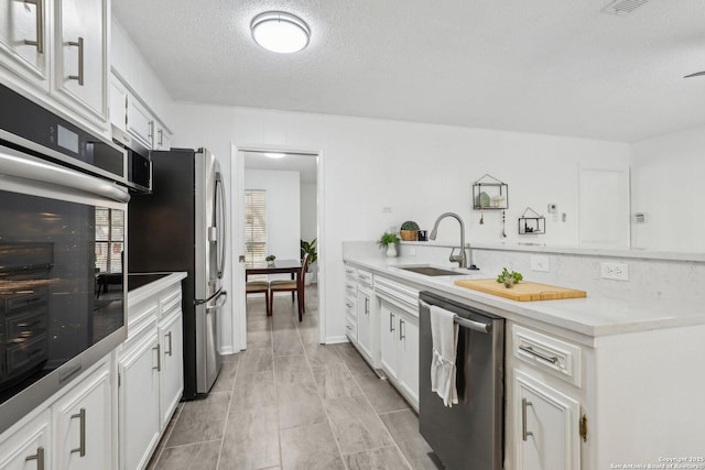 kitchen featuring stainless steel appliances, white cabinets, and light countertops