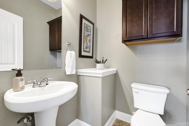 half bath featuring toilet and baseboards