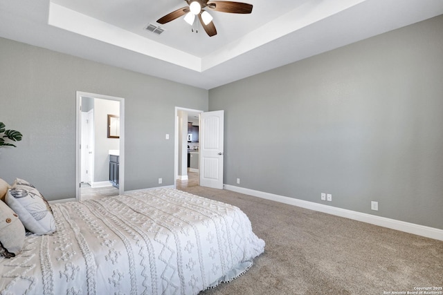 bedroom with light carpet, visible vents, baseboards, connected bathroom, and a tray ceiling