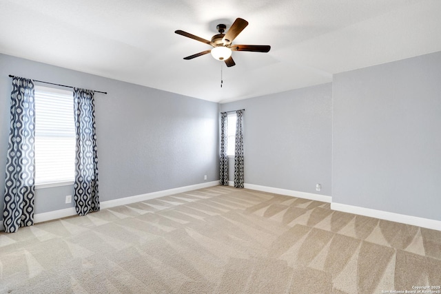 unfurnished room with baseboards, a ceiling fan, and light colored carpet