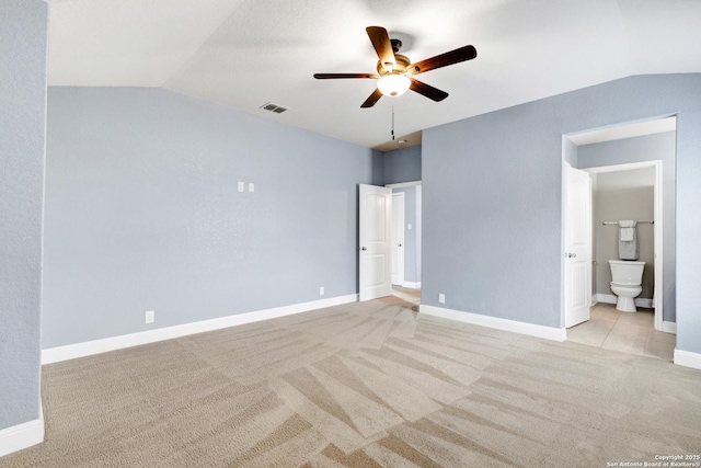 unfurnished bedroom with lofted ceiling, visible vents, light carpet, and baseboards