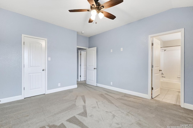 unfurnished bedroom with light carpet, connected bathroom, a ceiling fan, and baseboards