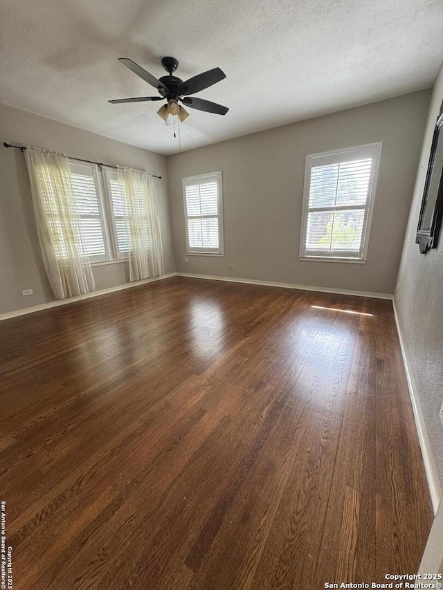spare room with a ceiling fan, baseboards, and dark wood-style flooring