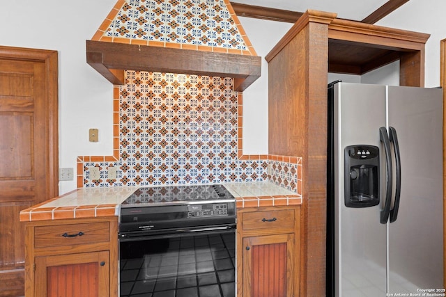 kitchen with tile countertops, electric stove, stainless steel refrigerator with ice dispenser, and decorative backsplash