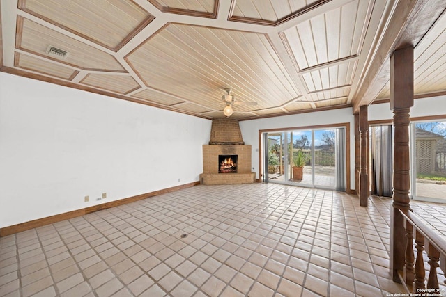 unfurnished living room featuring baseboards, a fireplace, wooden ceiling, and ornate columns