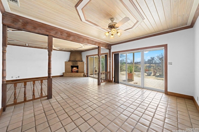 interior space with baseboards, a ceiling fan, wood ceiling, crown molding, and a brick fireplace