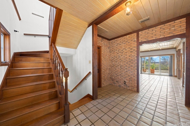 interior space featuring wooden ceiling, brick wall, visible vents, and tile patterned floors