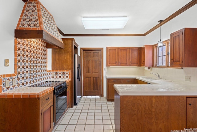 kitchen with custom exhaust hood, black electric range oven, hanging light fixtures, brown cabinetry, and a peninsula