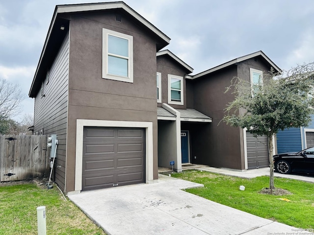 traditional-style home with a garage, concrete driveway, fence, a front lawn, and stucco siding