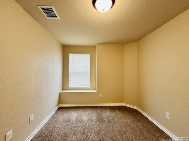 carpeted spare room featuring baseboards, visible vents, a textured ceiling, and a textured wall