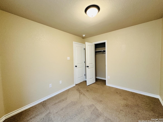 unfurnished bedroom with a textured ceiling, carpet floors, and baseboards